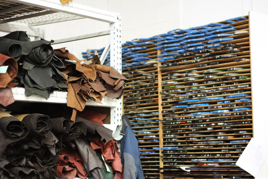 Rolls of uncut leather stack up on metal shelves.