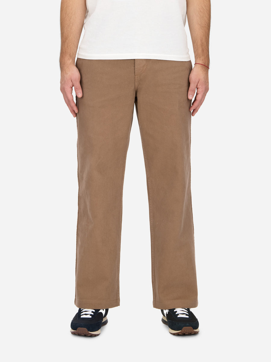 A person standing, wearing khaki twill work pants and a white t-shirt, with their hands at their sides.