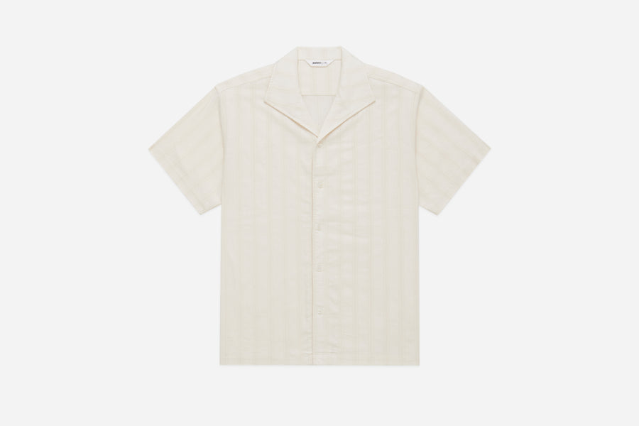 A beige leisure shirt with an open collar and short sleeves, featuring a Japanese striped lace weave and mother of pearl buttons.