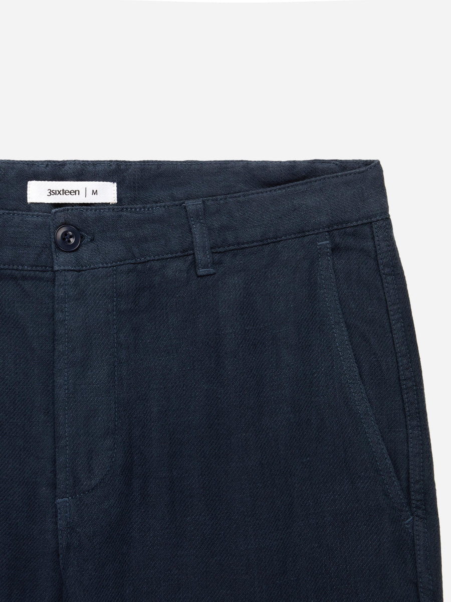 Close-up of dark blue pants with a brand label on a light gray background