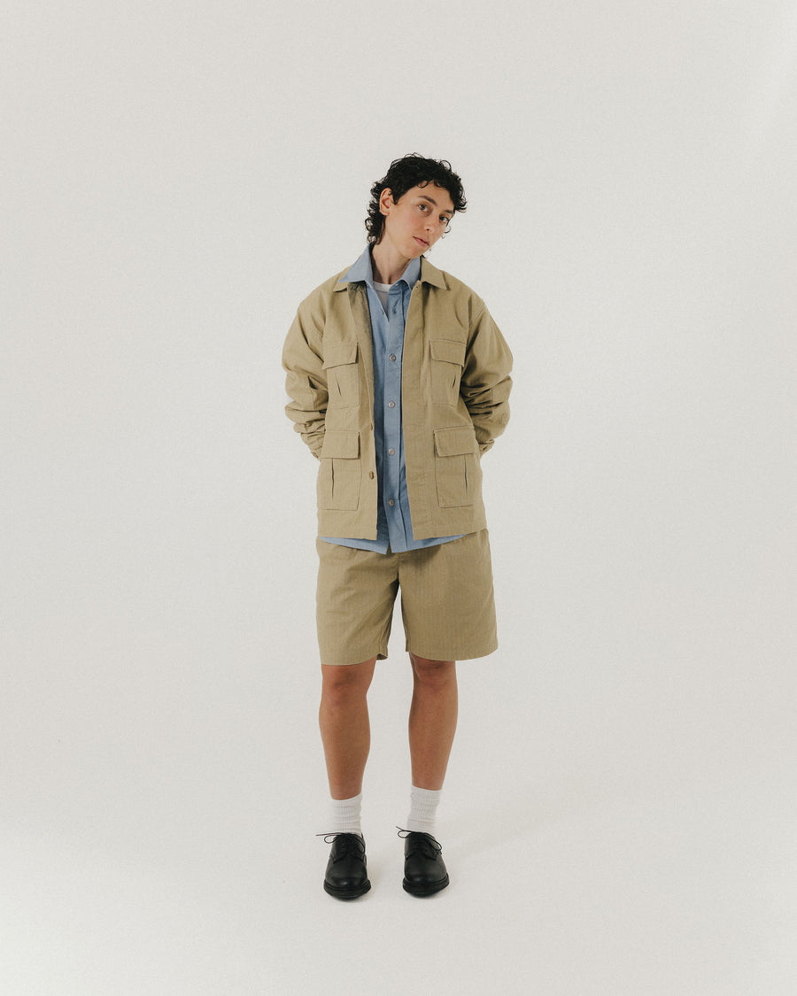 A woman in a tan military jacket and matching shorts.