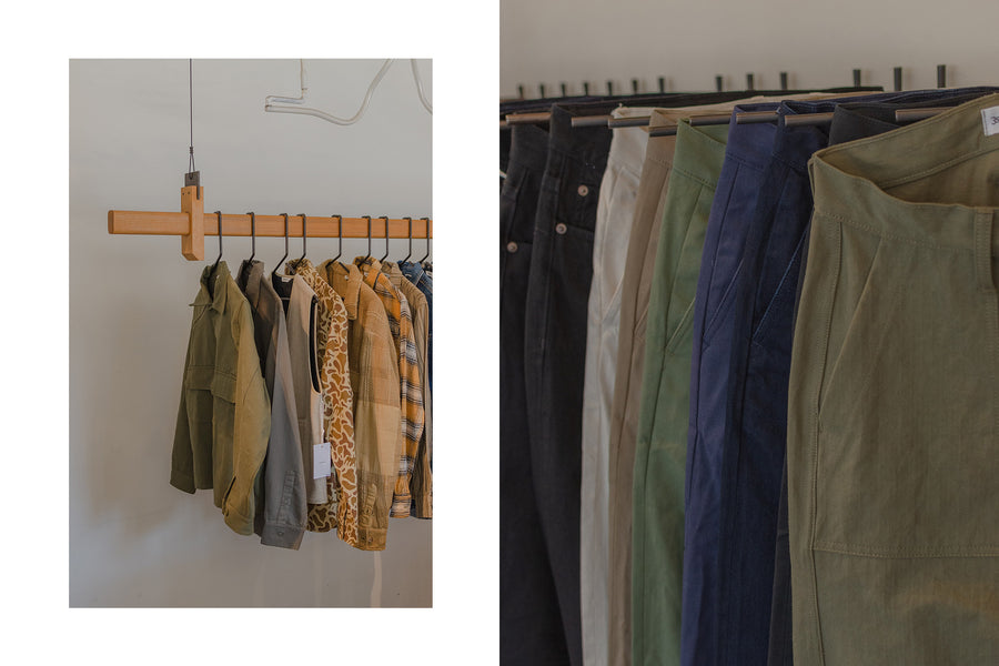 Clothing hangs on black metal hangers off a wooden rod.