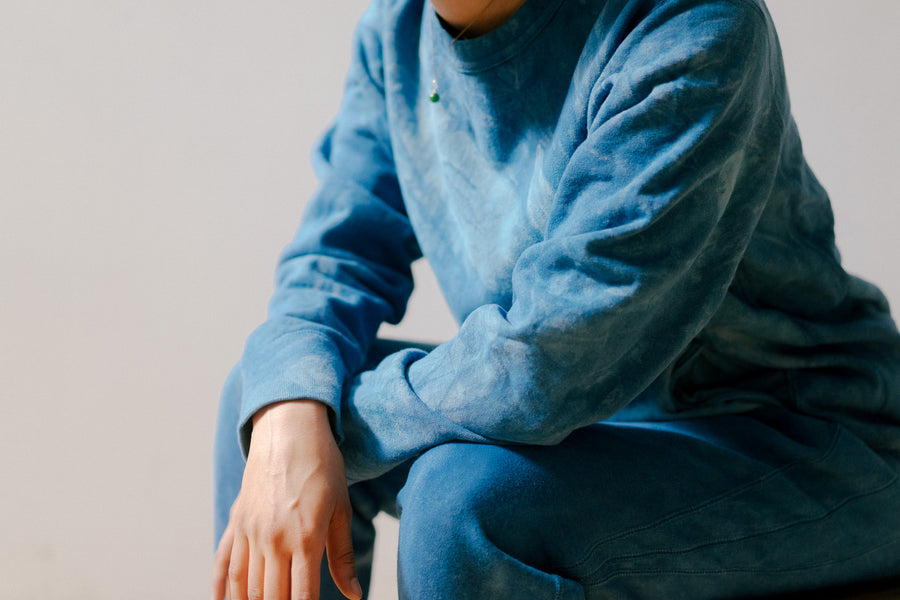 An up close at an indigo sweatsuit against a tan background